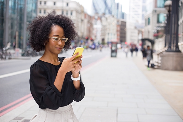 Woman checking bus route alerts on her phone on a city sidewalk