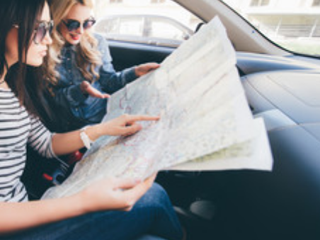 Two girls in vehicle looking at a map for directions